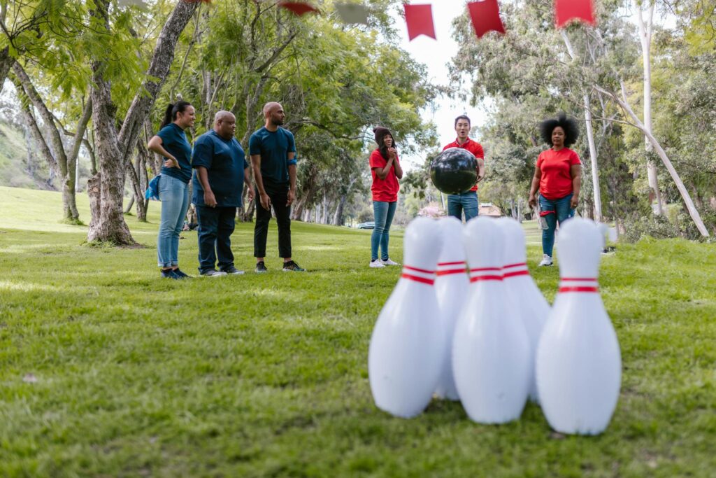 Group of diverse adults enjoying an outdoor bowling activity for team building in a park.